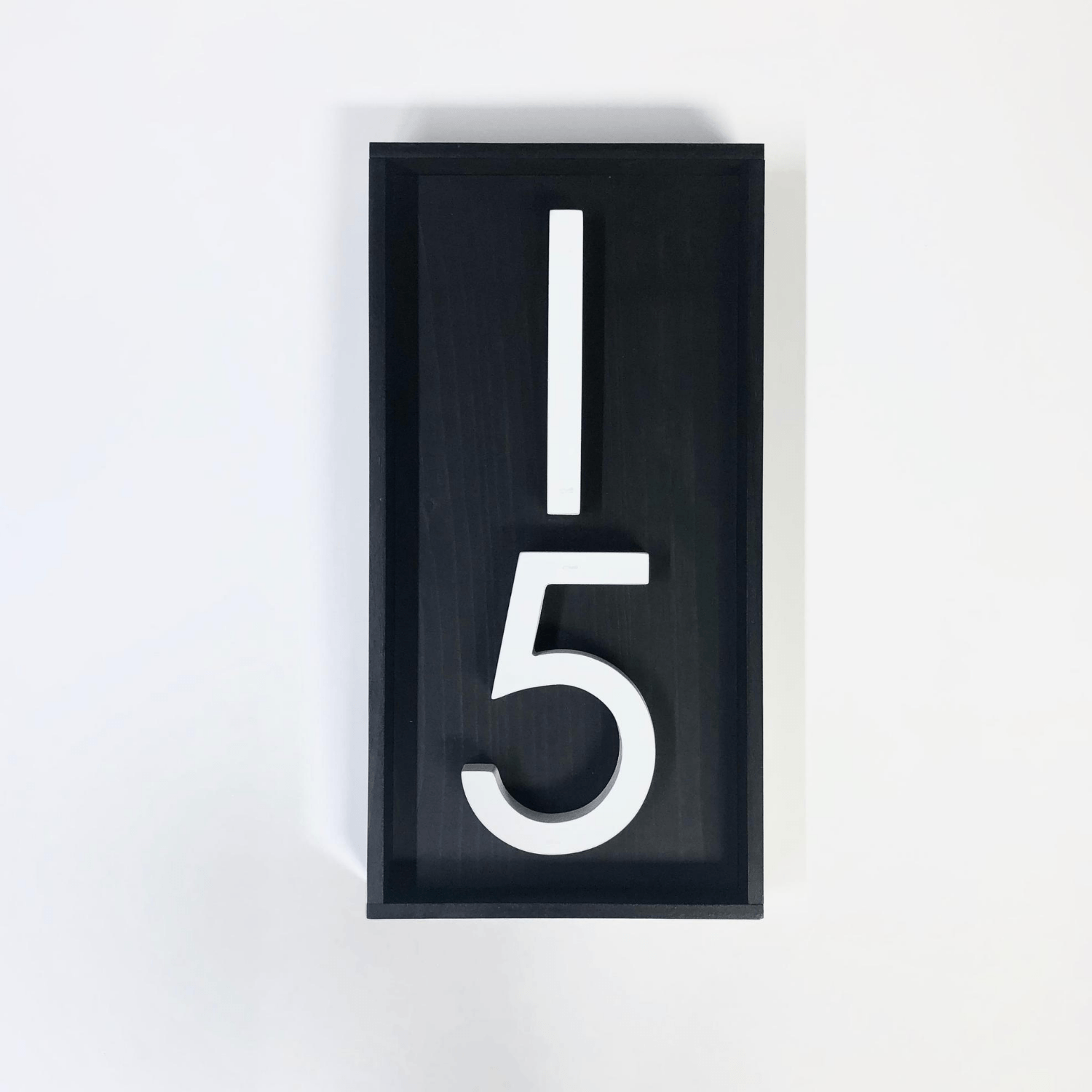 Black address sign with 2 white numbers placed vertically