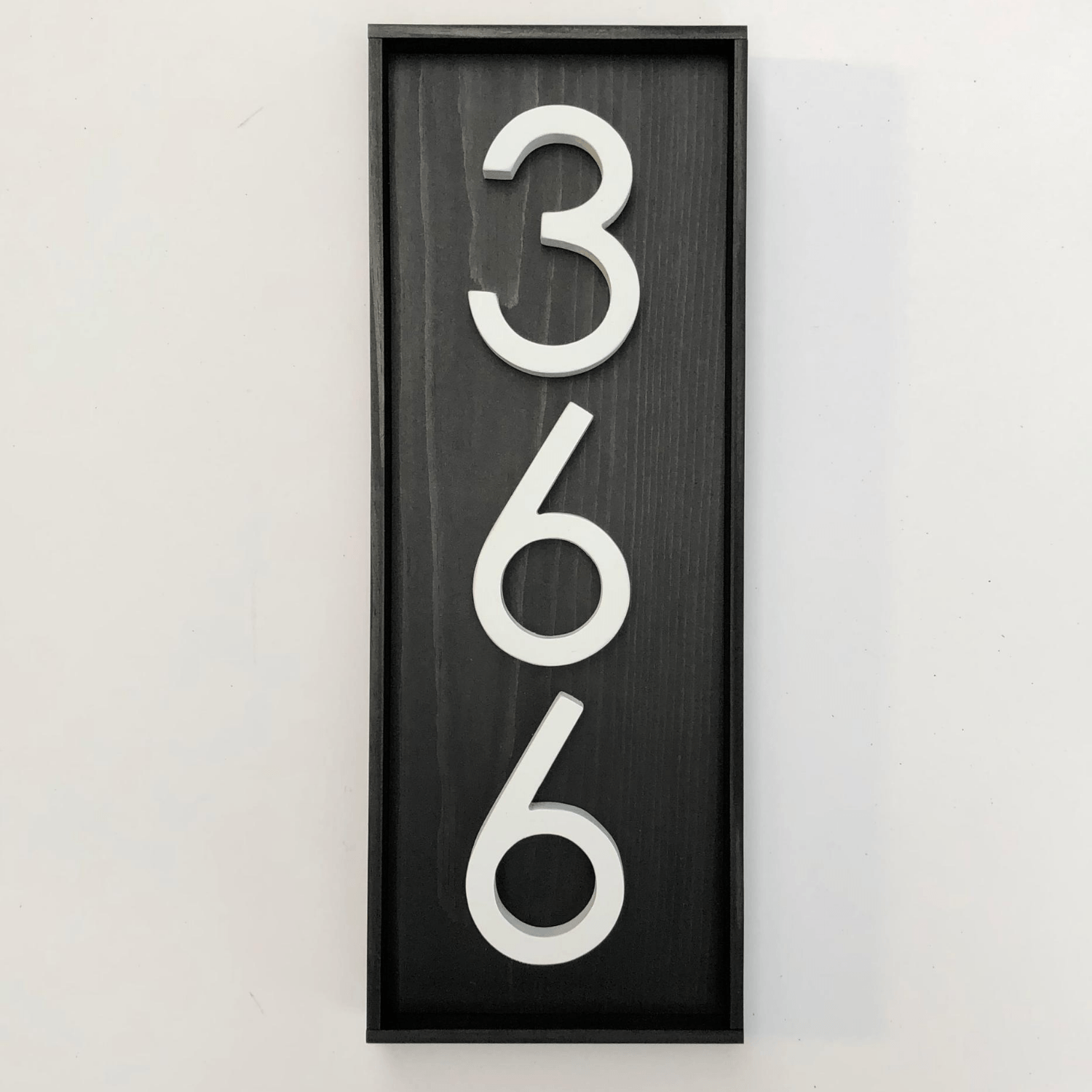 Vertical black address sign with 3 white numbers